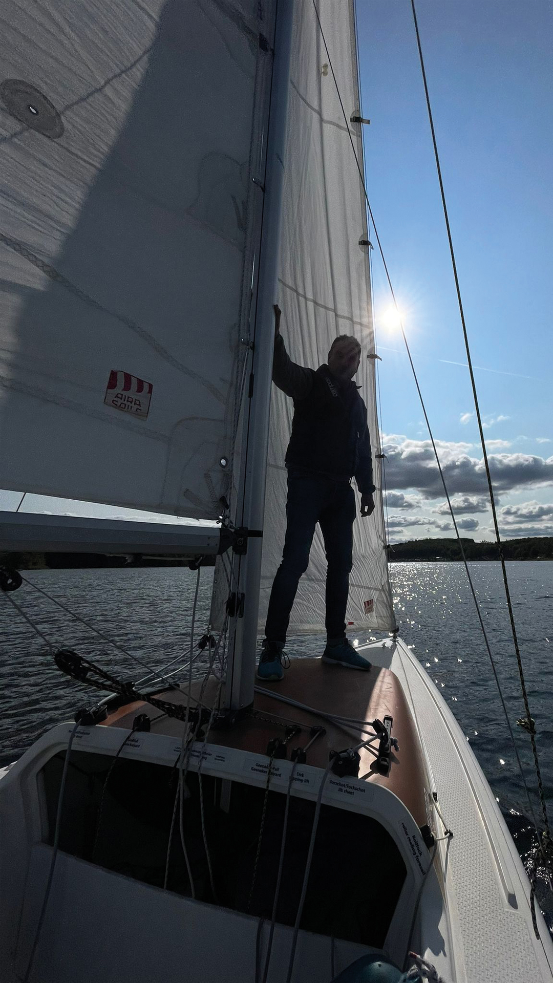 Jens Müller steht neben dem Mast eines Sportsegelboots.